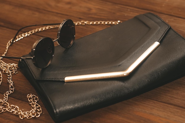 Schwarze Clutch mit Kette und Brille mit Eisenrand