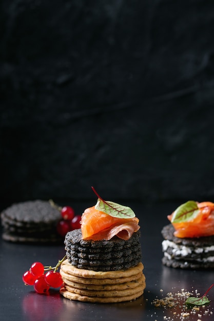 Schwarze Cracker mit Lachs und Beeren