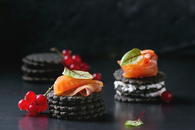 Schwarze Cracker mit Lachs und Beeren