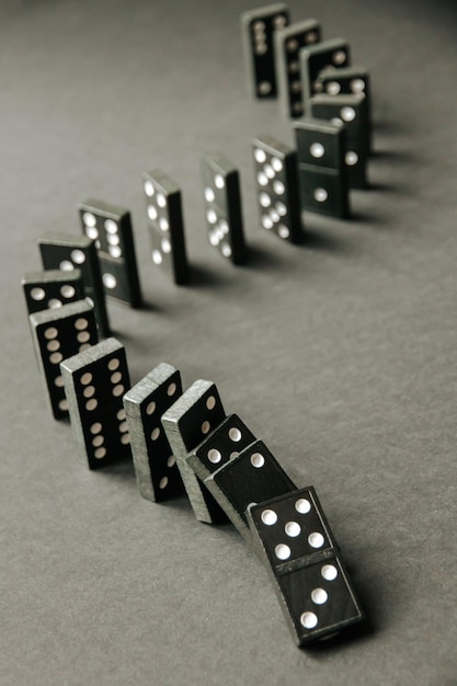 Schwarze Dominokette auf dunklem Tischhintergrund Domino-Effekt-Konzept