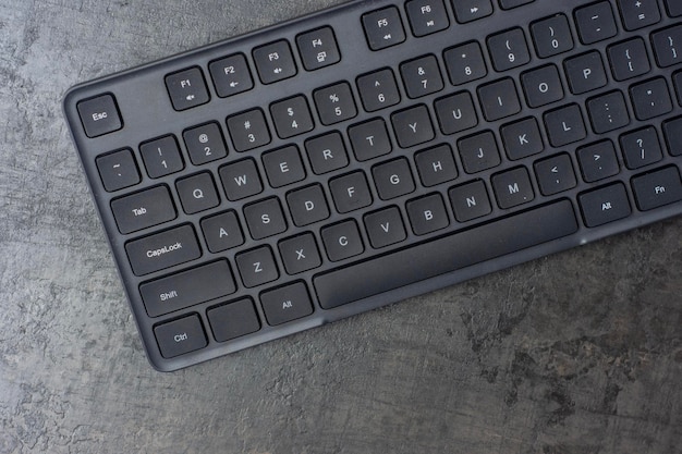 Schwarze drahtlose Computer-Tastatur auf einem dunklen Betontisch