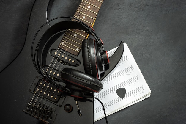 Schwarze E-Gitarre und Kopfhörer auf dem Boden.