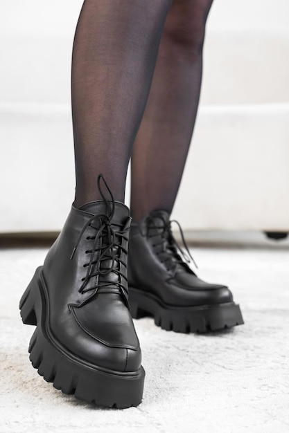 Schwarze elegante Schuhe der Nahaufnahme auf den Beinen der Frauen. Lederwinterstiefel, stylisches Damenschuh-Konzeptfoto