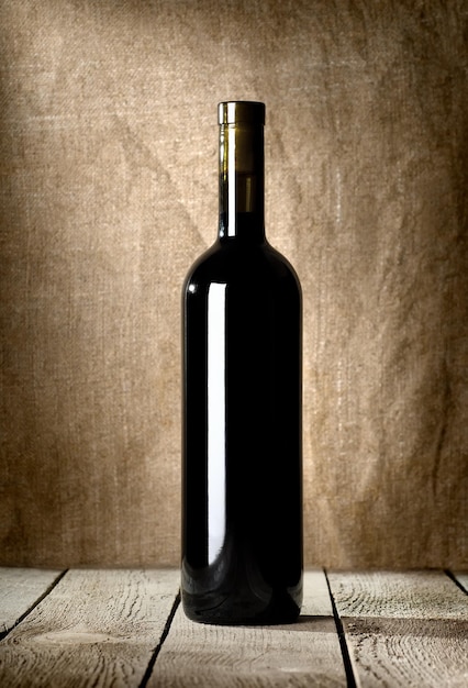 Schwarze Flasche Wein auf dem Hintergrund der Leinwand