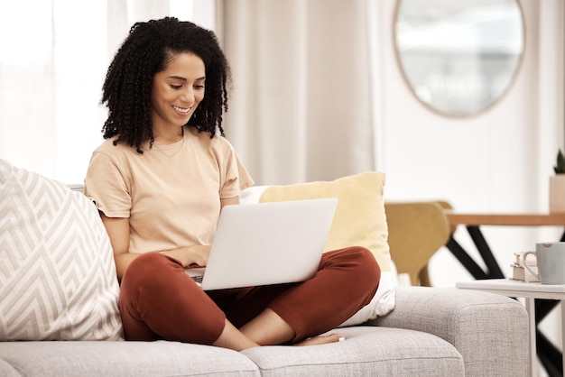 Schwarze Frau arbeitet und Laptop tippt in einem Wohnzimmer zu Hause und macht glückliche Arbeitsforschung Remote-Freiberufler, der an Webplanung und digitalem Marketing arbeitet, mit einem Lächeln auf einem Computer online in einem Haus