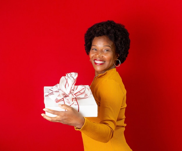 Schwarze Frau, die eine Geschenkbox in den Händen lächelt und hält