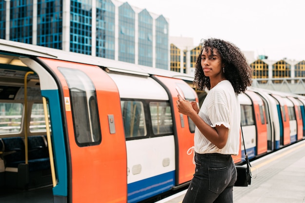 Schwarze Frau, die Handy bei London Underground verwendet