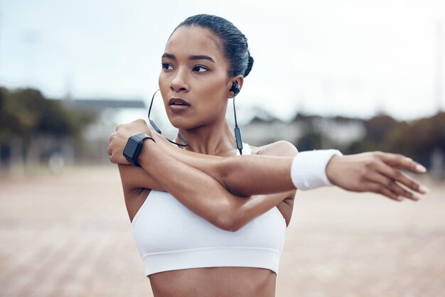 Schwarze Frau Fitness und Dehnübungen und Kopfhörer Musik und Motivation für einen aktiven Lebensstil im Freien Afroamerikanerin stark und konzentriert sich auf Cardio- und Ausdauertraining und gesundes Leben