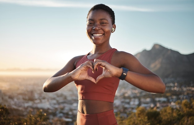 Schwarze Frau Fitness und Herz Hände auf dem Berg mit Musik für Outdoor-Sport Motivation Porträt Reisen Bewegung und Freiheit Afrikanische Frau glückliche Sportlerin und Liebeszeichen zum Wandern mit Podcast