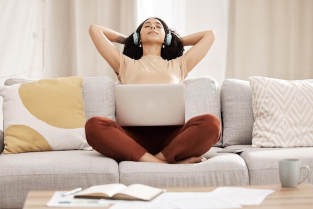 Schwarze Frau Kopfhörer und Laptop zum Entspannen auf der Couch für Wellness und Meditation im Wohnzimmer Junge weibliche Mädchen und Kopfhörer für Podcast-Ruhe und Pause für Gesundheit ruhig und friedlich auf dem Sofa