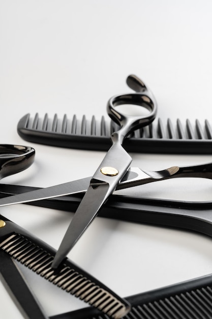 Schwarze Friseurinstrumente und verschiedene Haarbürsten auf weißem Hintergrund