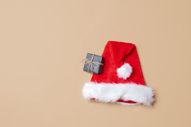 Schwarze Geschenkbox und Weihnachtsmann-Hut auf stark weißem Hintergrund. Ansicht von oben