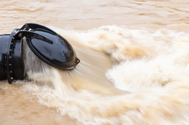 Schwarze große Wasserleitung beim Pumpen des Überschwemmungswassers in den Fluss