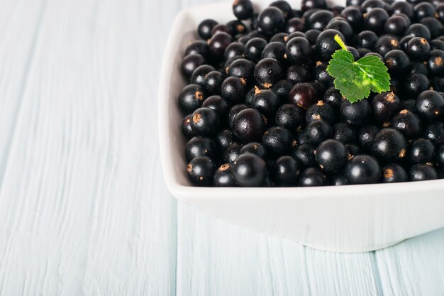 Schwarze Johannisbeere auf Holztisch mit Blattzweig