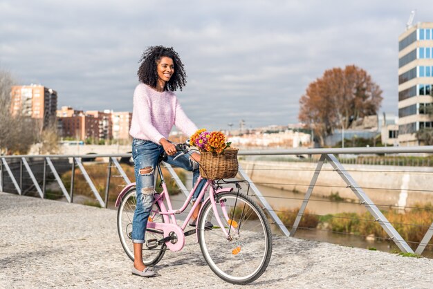 Schwarze junge Frau, die Weinlesefahrrad fährt