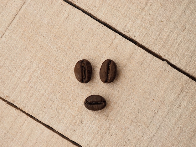 Schwarze Kaffeekörner liegen auf hellem Holztisch, Hintergrundbild. Platz für Text