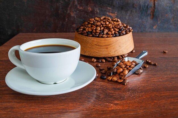 schwarze Kaffeetassen und Kaffeebohnen, geröstet auf einem Holztisch