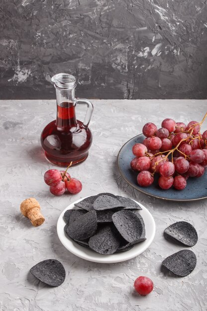 Foto schwarze kartoffelchips mit holzkohle, balsamico-essig und roten trauben