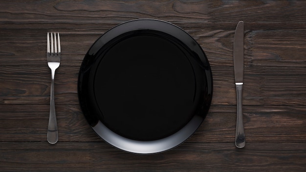 Schwarze Keramikplatte mit Gabel und Messer