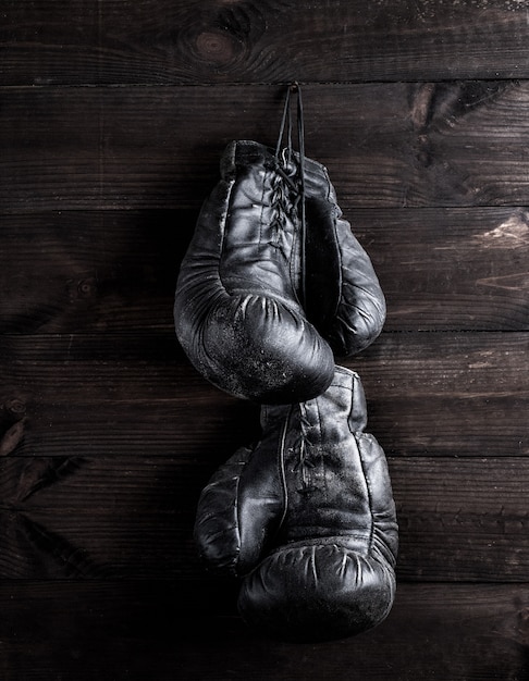 schwarze lederne Boxhandschuhe, die an einem Nagel hängen