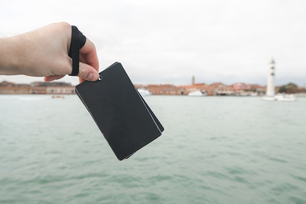 Schwarze leere Karte in der Hand eines Mannes auf der Seelandschaft. Konzentriere dich auf eine schwarze Karte