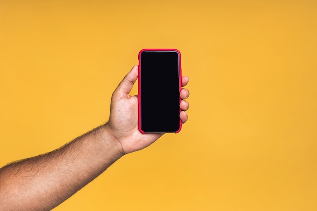 Foto schwarze männliche afroamerikanische indische hand, die das handy-display berührt und mit dem zeigefinger auf den leeren bildschirm zeigt, einzeln auf gelbem hintergrund, kopierraum, ausschnitt.