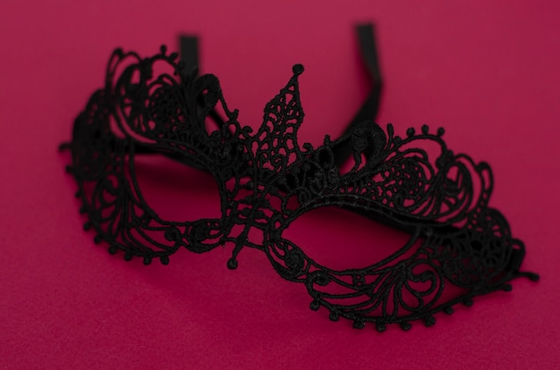 Schwarze Maske auf dunklem rosa Hintergrund