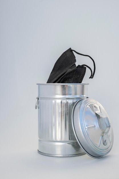 Schwarze Maske in einem Mülleimer auf grauem Hintergrund Nahaufnahme Kein organischer Abfall