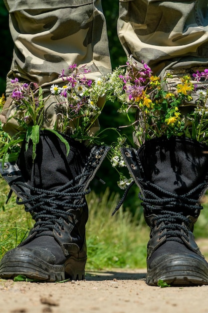 Schwarze Militärstiefel mit Blumen Konzept Blumen statt Kugeln und Krieg Beendigung des Krieges in der Ukraine Die Kapitulation der russischen Armee und der Abzug der Truppen aus dem Territorium der Ukraine