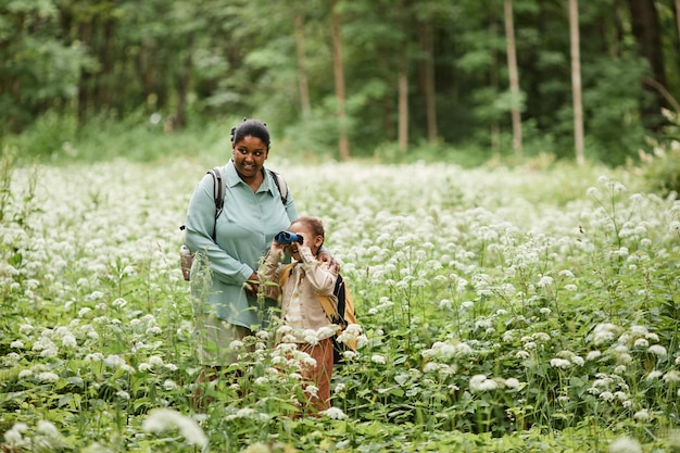 Schwarze Mutter und Tochter wandern und schauen im Fernglas