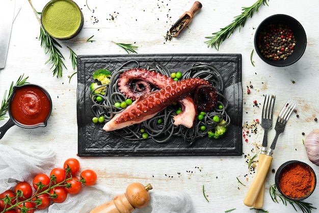 Schwarze Pasta mit Oktopus-Tentakeln auf einer schwarzen Steinplatte Draufsicht von Meeresfrüchten Freier Platz für Ihren Text