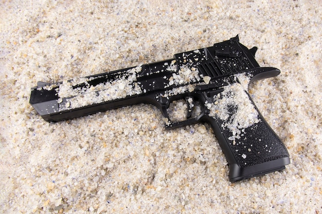 Schwarze Pistole liegt im Sand