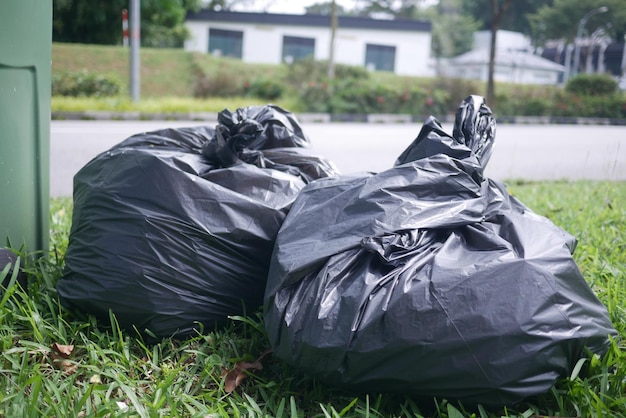 Schwarze Plastiktüte mit Müll und Mülleimer