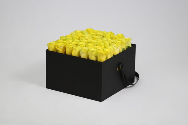 Schwarze quadratische Geschenk-Blumenbox mit gelben Rosen im Inneren
