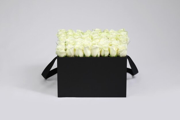 Schwarze quadratische Geschenk-Blumenbox mit weißen Rosen im Inneren