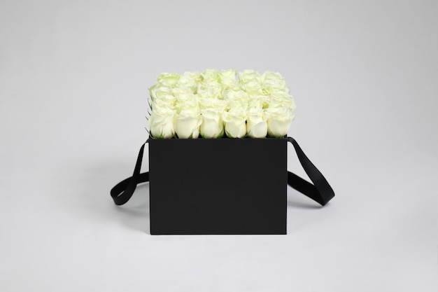 Schwarze quadratische Geschenk-Blumenbox mit weißen Rosen im Inneren