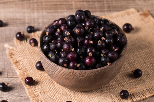 Schwarze Rosinen in einer Schüssel auf Holzgrund Bio-Beeren