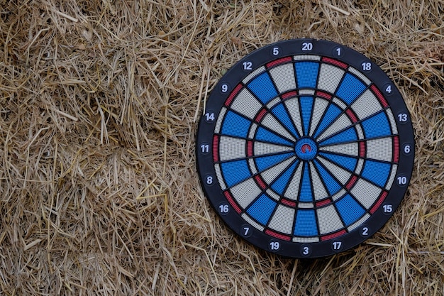 Schwarze, rote, blaue und weiße runde Dartscheiben hängen draußen an einer Vintage-Strohwand und sorgen für Unterhaltung im Garten oder auf der Terrasse