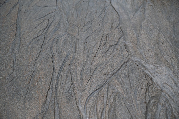 Schwarze Sanddünen Schwarzer Sandstrand Makrofotografie Hintergrundtextur Wellenmuster des ozeanischen Sandes am Strand