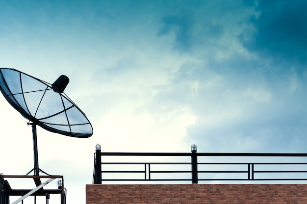 Schwarze Satellitenschüssel oder Fernsehantennen auf dem Gebäude mit dem blauen Himmel bewölkt