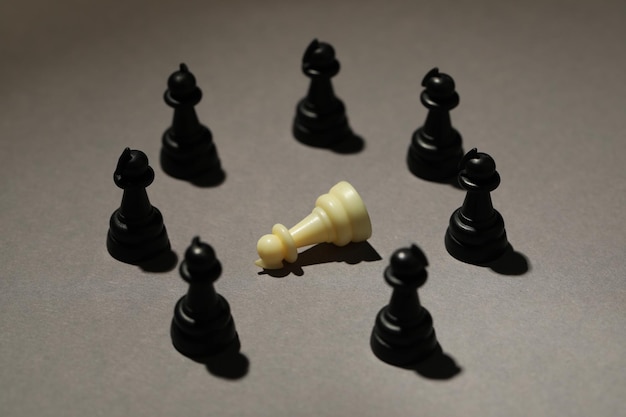 Schwarze Schachfiguren und weiße auf grauem Hintergrund Mobbing-Konzept