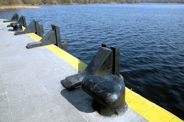 Foto schwarze schwere stangen am leeren fluss pier rand am meer diagonalen blick an einem sonnigen tag