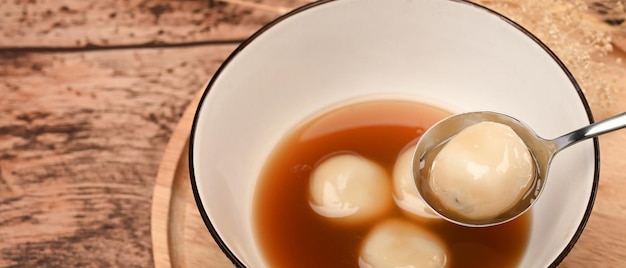 Schwarze Sesamknödel in heißer Ingwersuppe auf Holztisch.