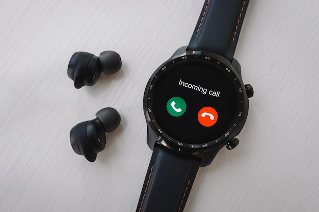 Schwarze Smartwatch und kabellose Kopfhörer auf weißem Hintergrund Eingehender Anruf auf einer modernen Smartwatch