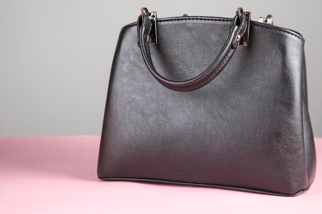 Schwarze Tasche auf dem rosa Tisch