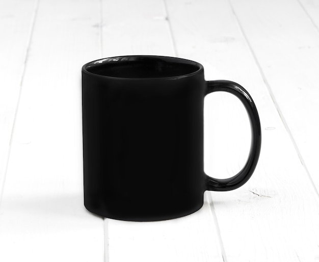 Schwarze Tasse auf einem beplankten Tisch