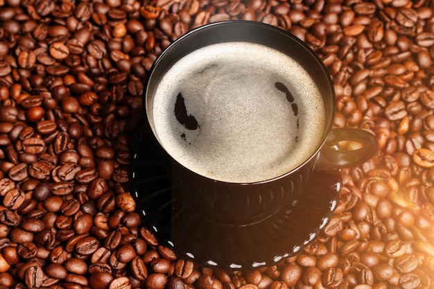 Schwarze Tasse mit aromatischem schwarzen Kaffee mit Schaum auf einem Hintergrund von Kaffeebohnen guten Morgen Tapete ...