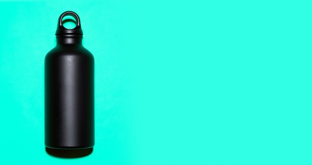 Schwarze wiederverwendbare Thermo-Wasserflasche aus Aluminium auf Cyan mit Kopierraum.