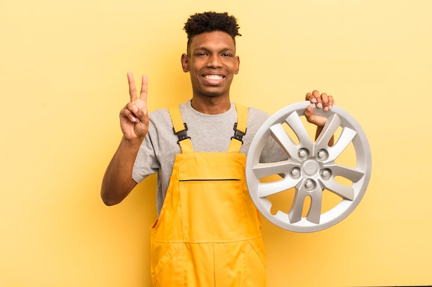 Schwarzer Afro-Junger lächelt und sieht freundlich aus und zeigt das Konzept des Automechanikers Nummer zwei