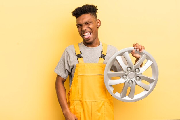 Schwarzer Afro-Junger Mann mit fröhlicher und rebellischer Haltung, der scherzt und die Zunge herausklebt, Automechaniker-Konzept